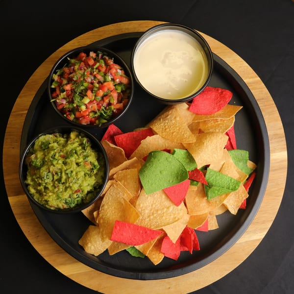 Bueno Burrito's colorful tortilla chips with bowls of guacamole, salsa, and queso dip.