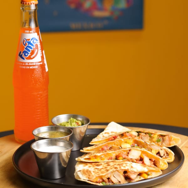 Bueno Burrito's chicken quesadillas with salsa, guacamole, sour cream, and a Fanta soda.